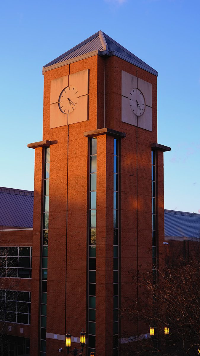 A tall brick clock tower with a clock on each of it's sides; UNC Charlotte's Student Activity Center